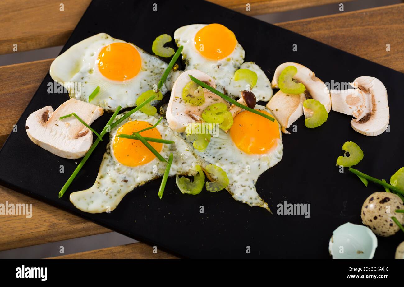 Broken fried quail eggs with mushrooms Stock Photo