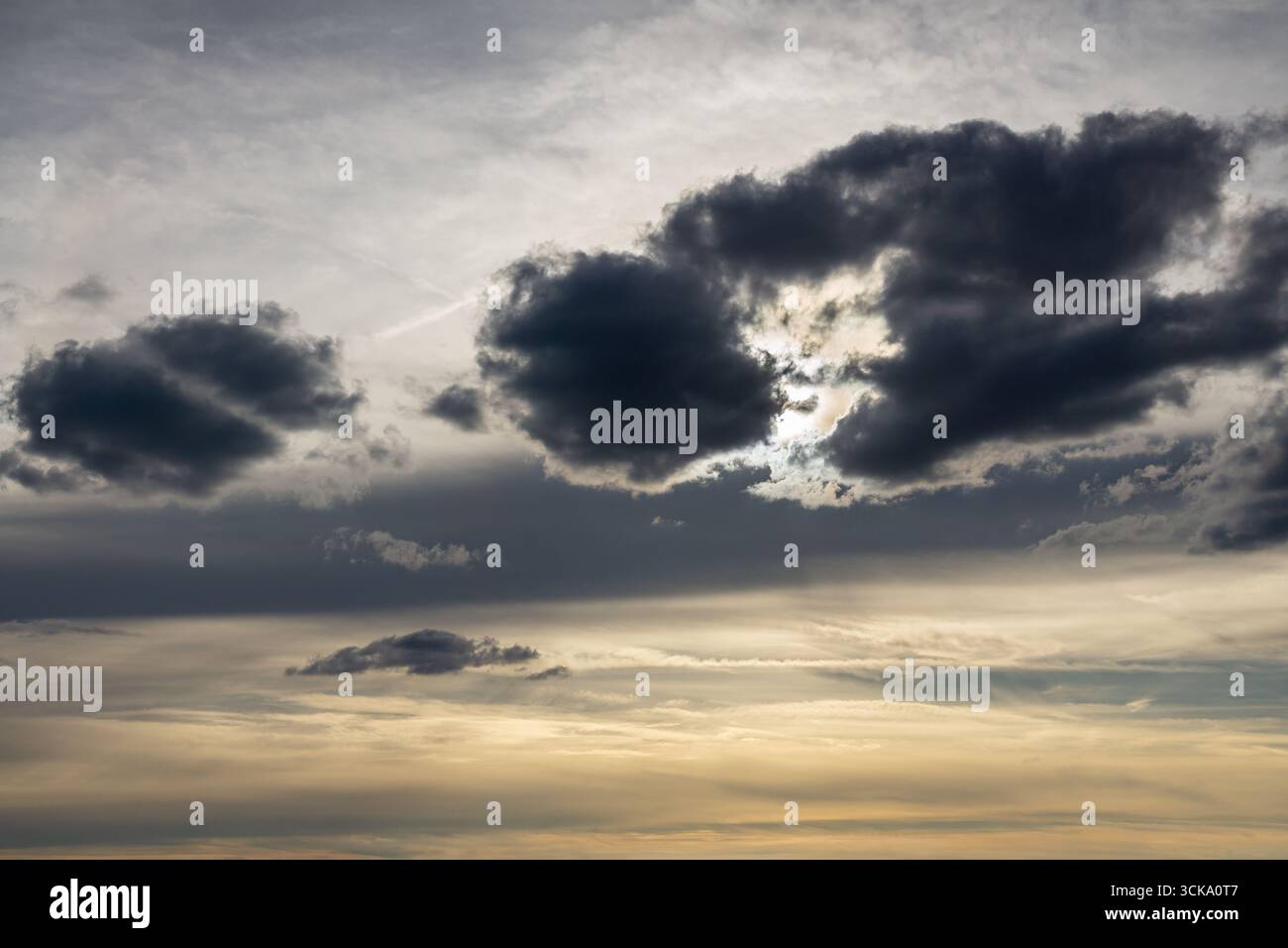Dramatic sky with sun rays breaking through dark storm clouds and moody atmosphere. Stock Photo