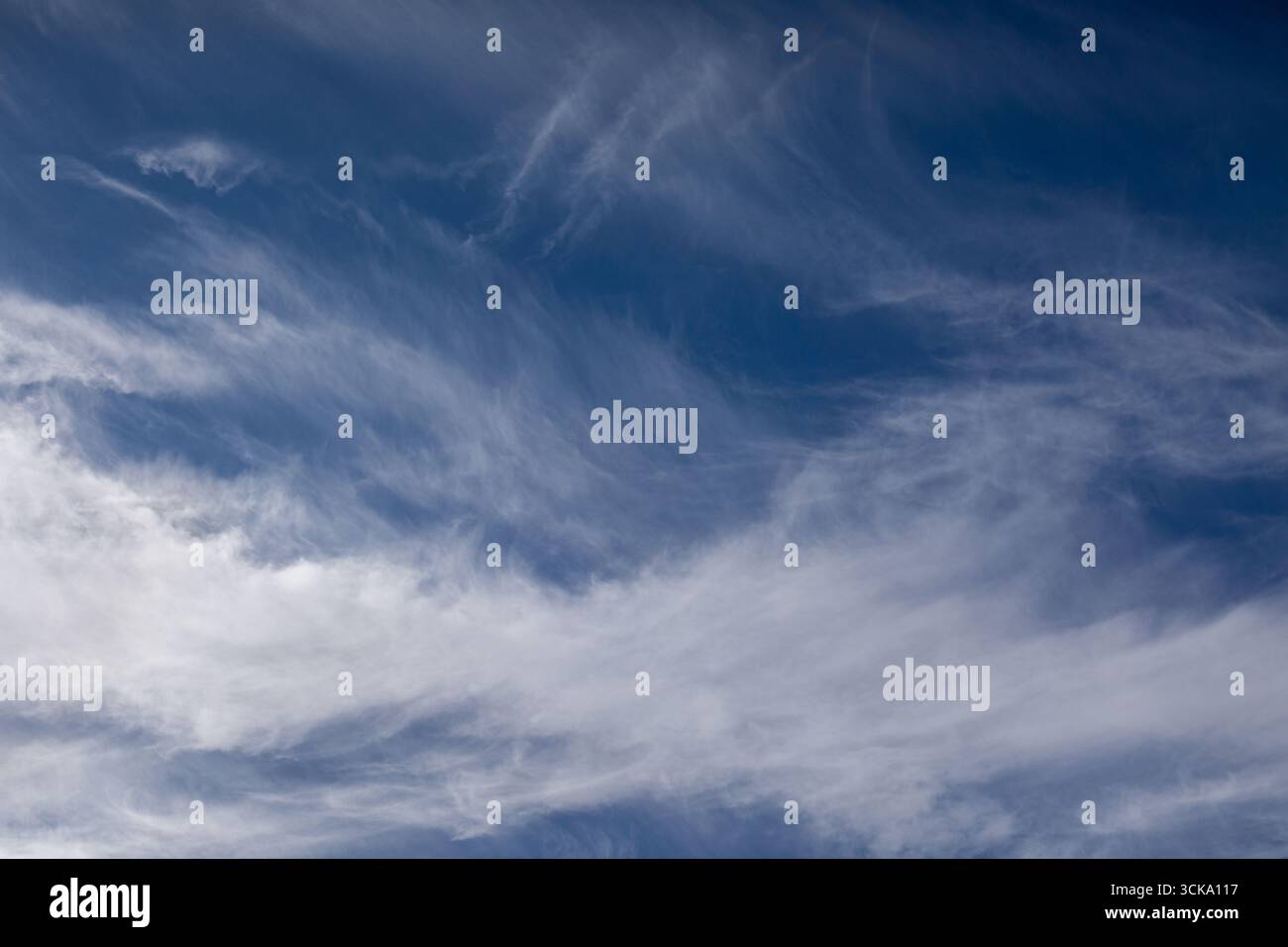 Wispy cirrus clouds drifting across blue sky with delicate natural patterns. Stock Photo