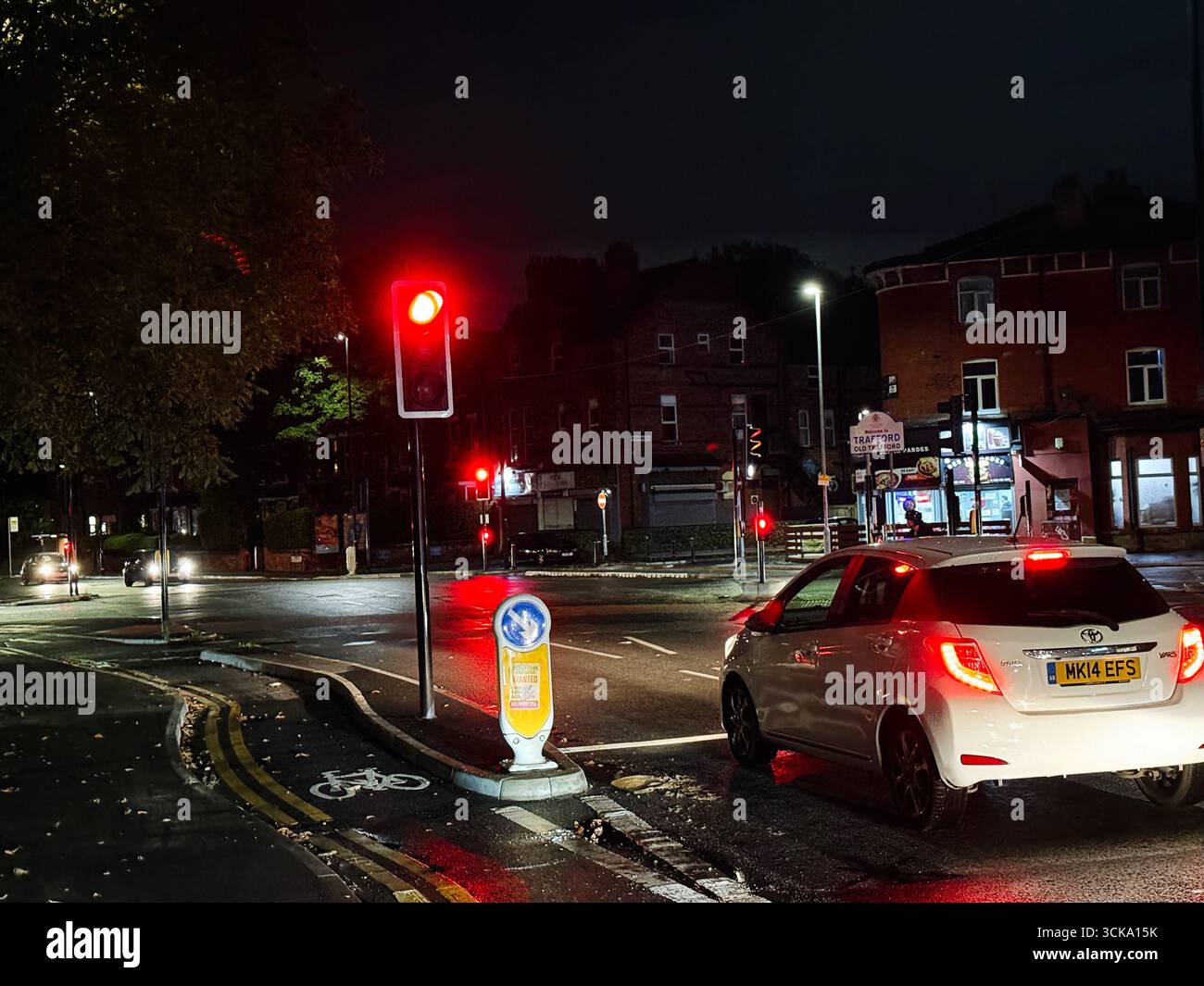 Manchester, UK - September 10, 2025: An illuminated intersection featuring vehicles halted at a red traffic light, Manchester. Stock Photo