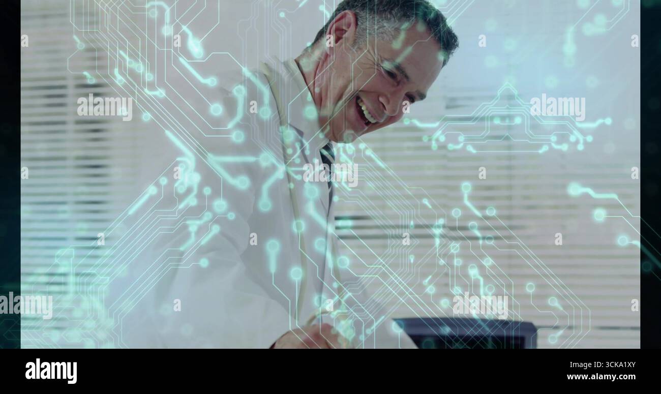 Smiling professional leaning over desk working on laptop in office, with circuit-pattern overlay Stock Photo