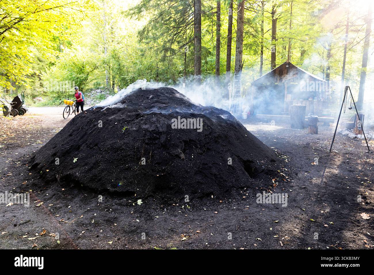 Tourist on a cycling, bikepacking trip around Slovenia, exploring beautiful mountain landscape, visiting charcoal pile site in radovna valley Stock Photo