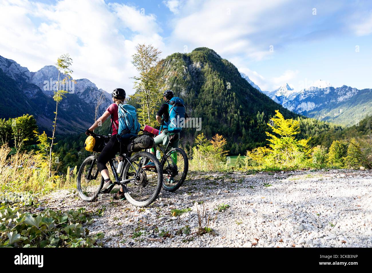 Tourists on a cycling, bikepacking trip around Slovenia, exploring beautiful mountain landscape in radovna valley near mojstrana Stock Photo
