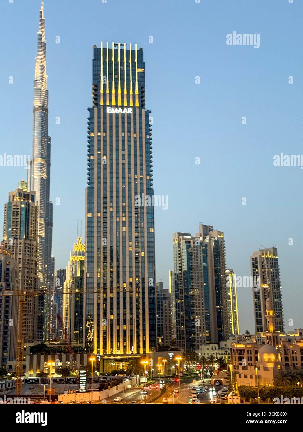 As the sun sets, the lights come to life over downtown Dubai in the United Arab Emirates.  The skyline of the thin- shaped well-known Burj Khalifa tow - Smartphone Captured Stock Image
