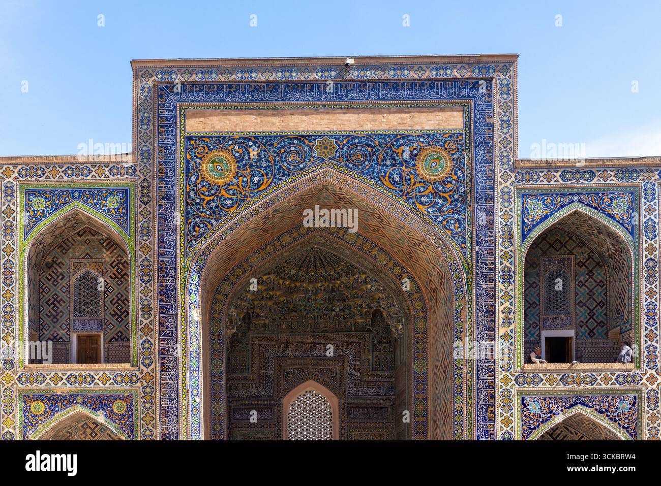 Samarkand, Uzbekistan - March 25, 2024: Sher-dor Madrasah placed at the Registan square on a sunny day. Visitors are at the balcony Stock Photo