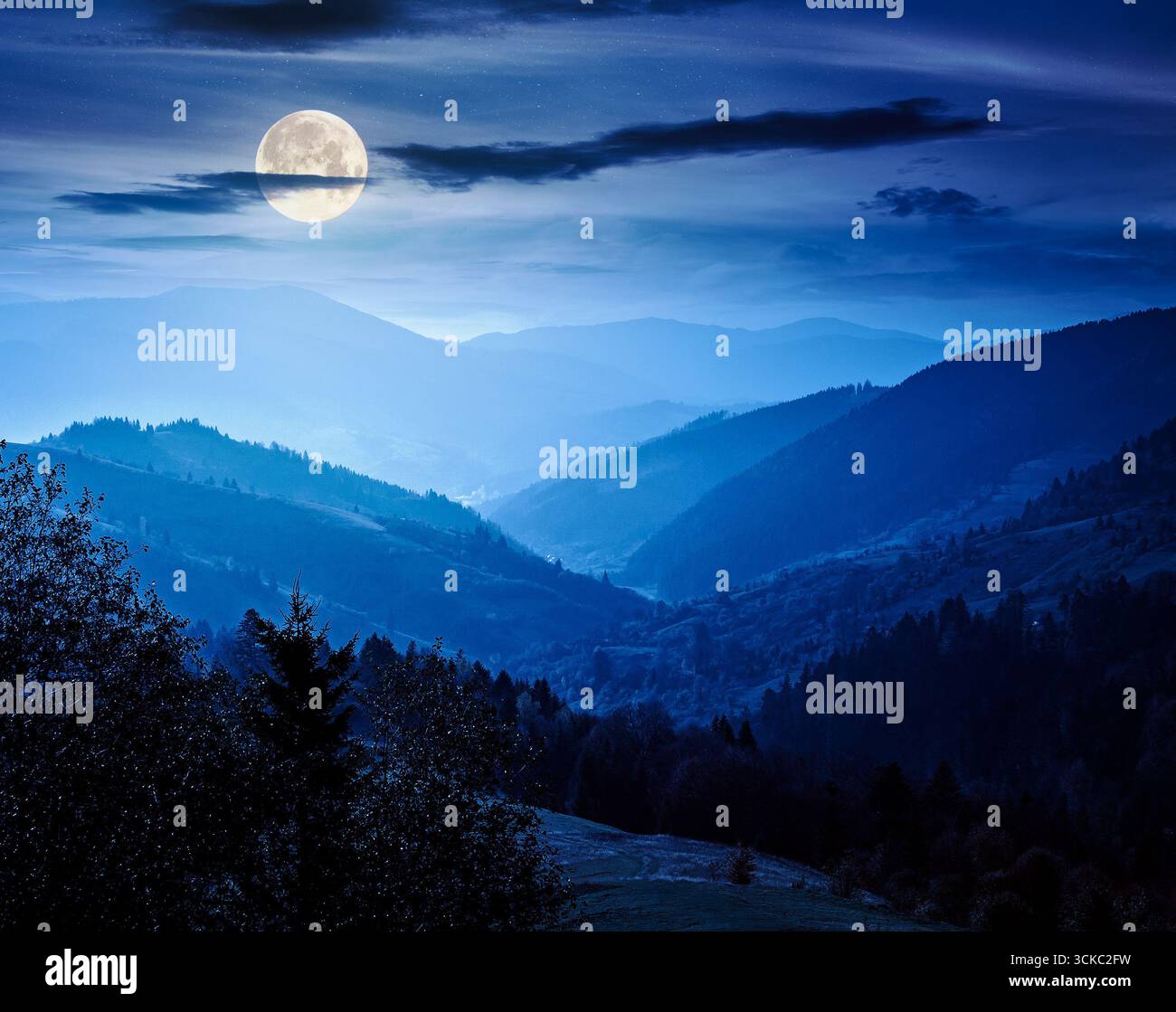 beautiful afternoon in carpathian mountains at night. scenic autumn weather. forest in colorful foliage. distant valley in haze and full moon light Stock Photo