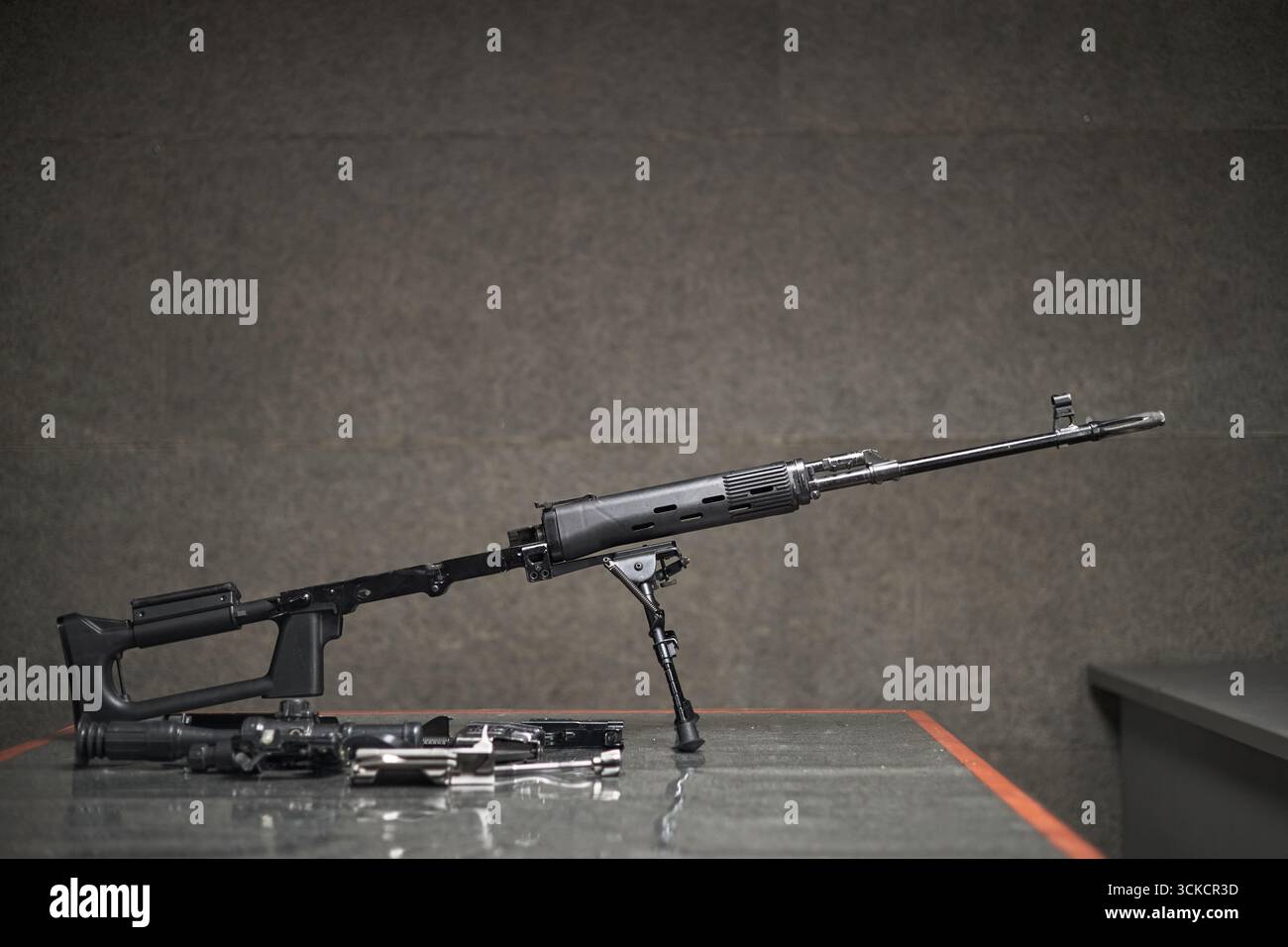 Modern semi automatic rifle standing on bipod with disassembled firearm ...