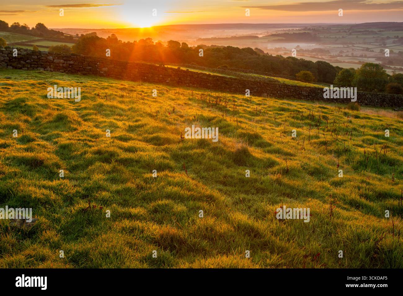 Early autumn sunrise view with the sun rising over distant moors looking along the Esk valley within the North York Moors national park - Stock Image