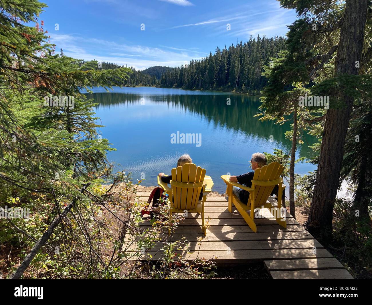 Two people in Adirondack chairs enjoying lake view. Battleship Lake, Strathcona Provincial Park, Vancouver Island, British Columbia, Canada. - Smartphone Captured Stock Image