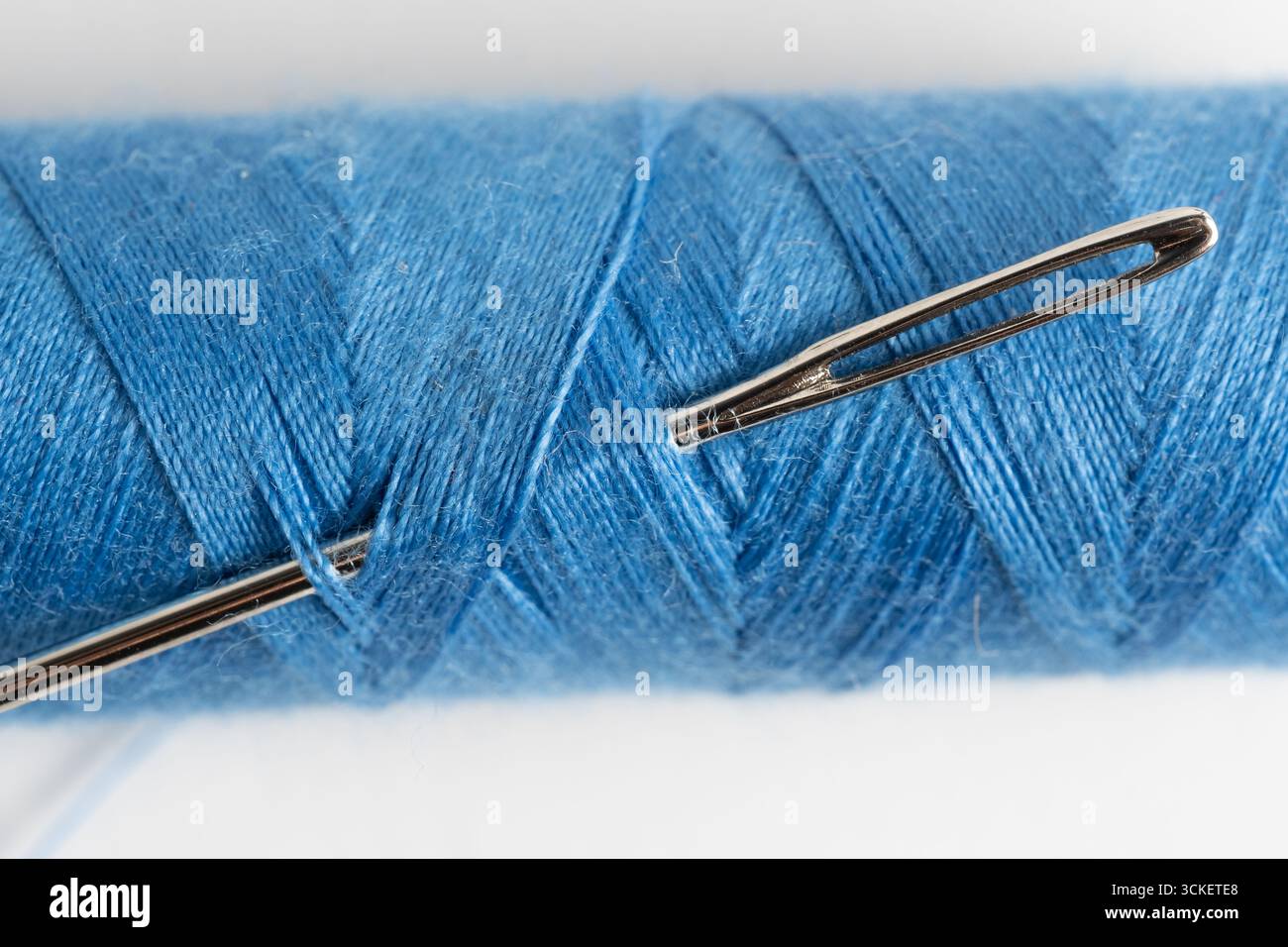 Sewing threads and needle on white background. Close up Stock Photo