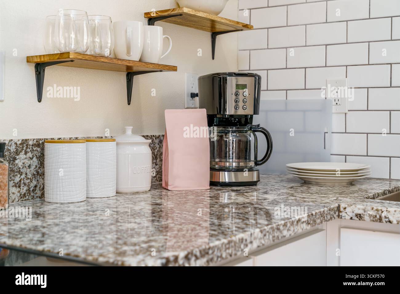 Coffee maker in bright white kitchen corner with ceramic jars, plates cups Stock Photo