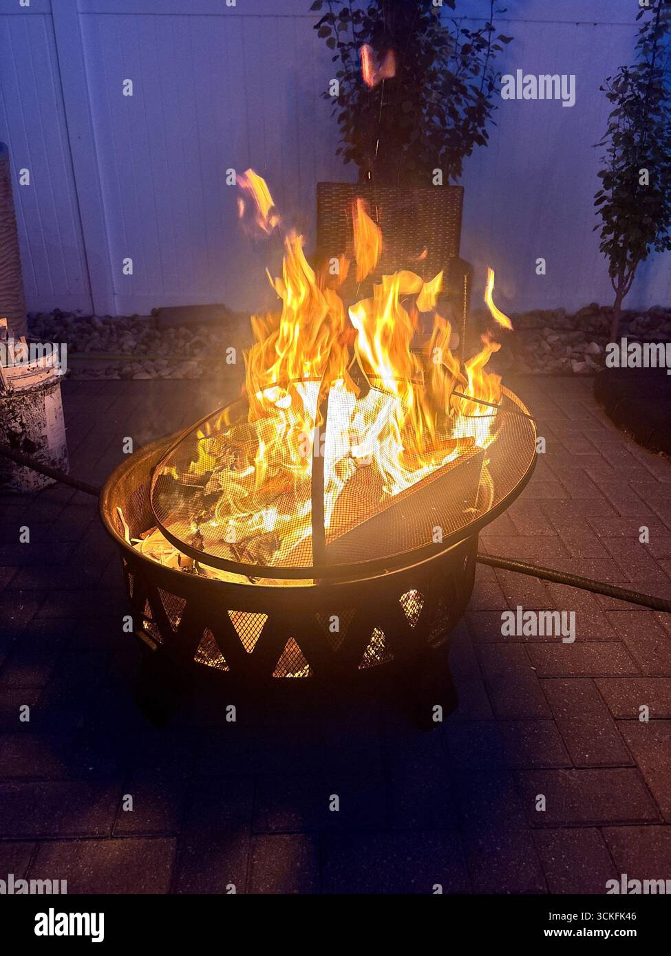 ''Cozy outdoor backyard fire pit with bright flames burning on a cool evening.'' - Smartphone Captured Stock Image