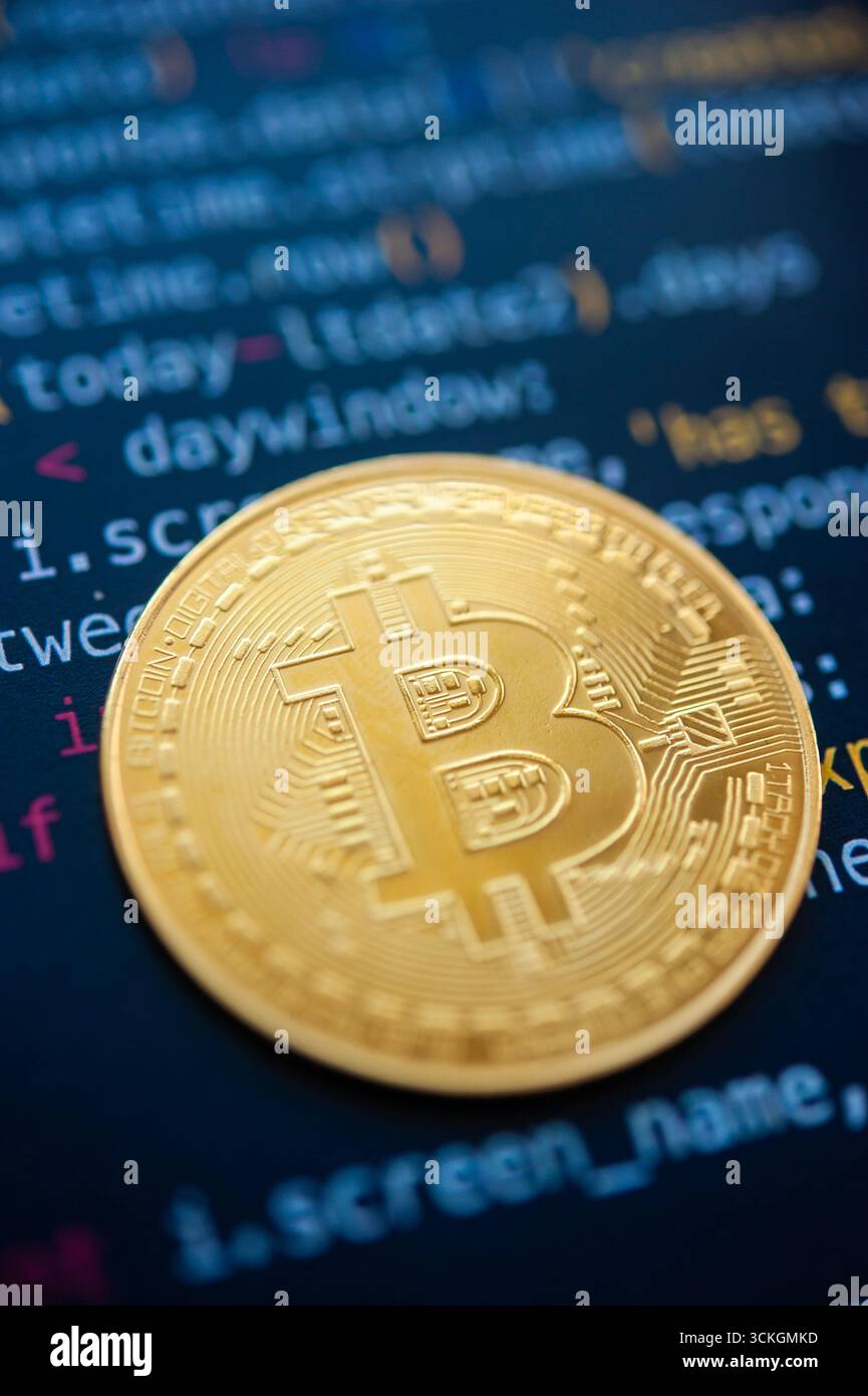 Golden bitcoin coin over computer code symbolizing cryptocurrency technology and blockchain system Stock Photo