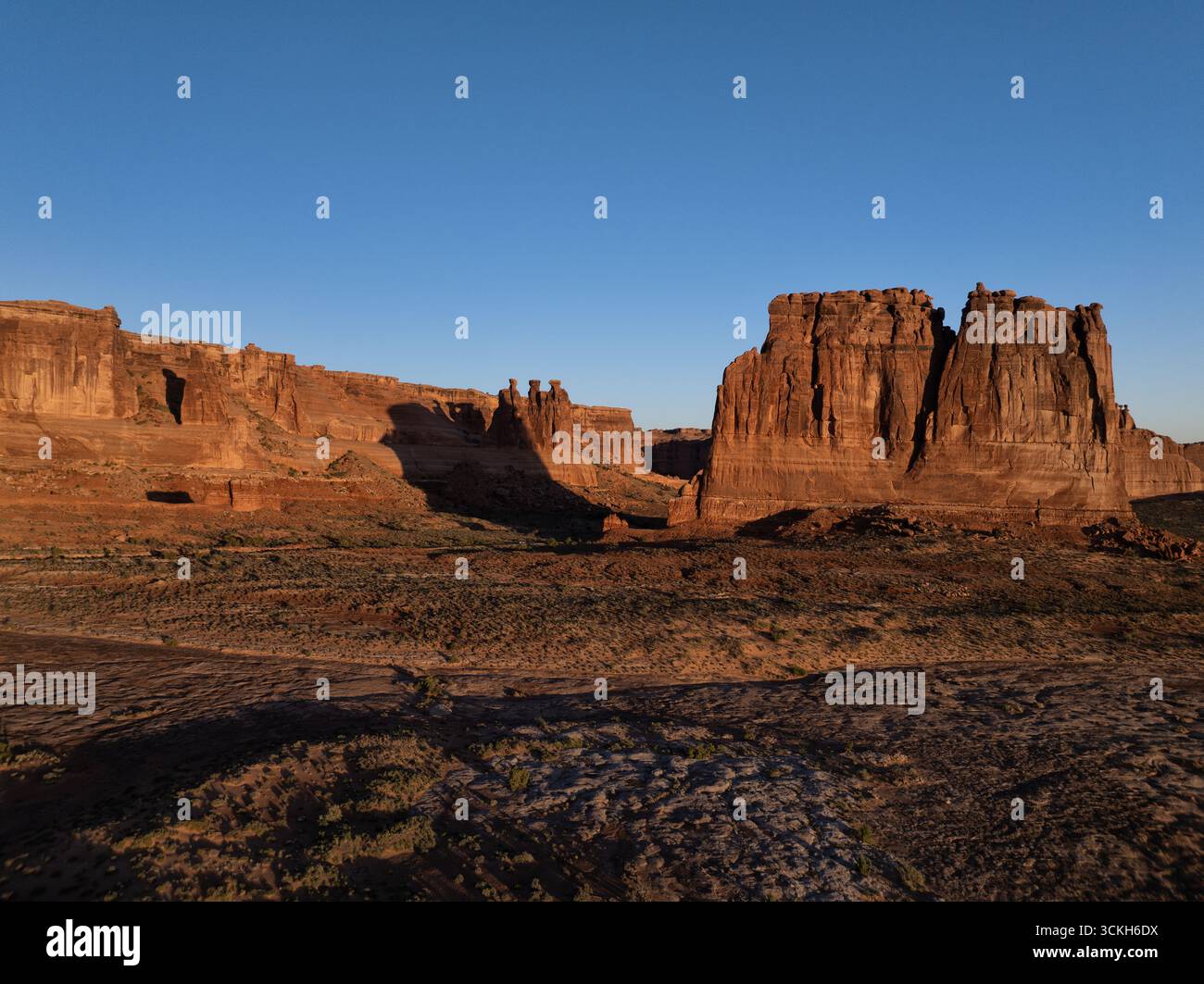 Aerial view of golden sunlight kissing the rugged cliffs and mesas, casting long shadows across the arid landscape of Grand County, Utah, United State Stock Photo