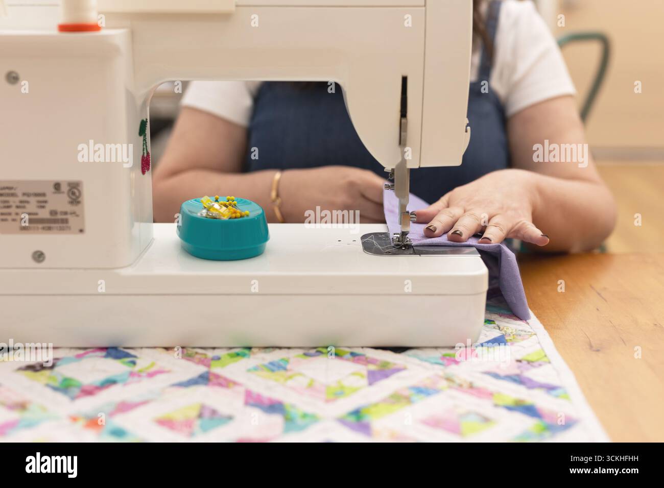 Woman using sewing machine with purple fabric Stock Photo