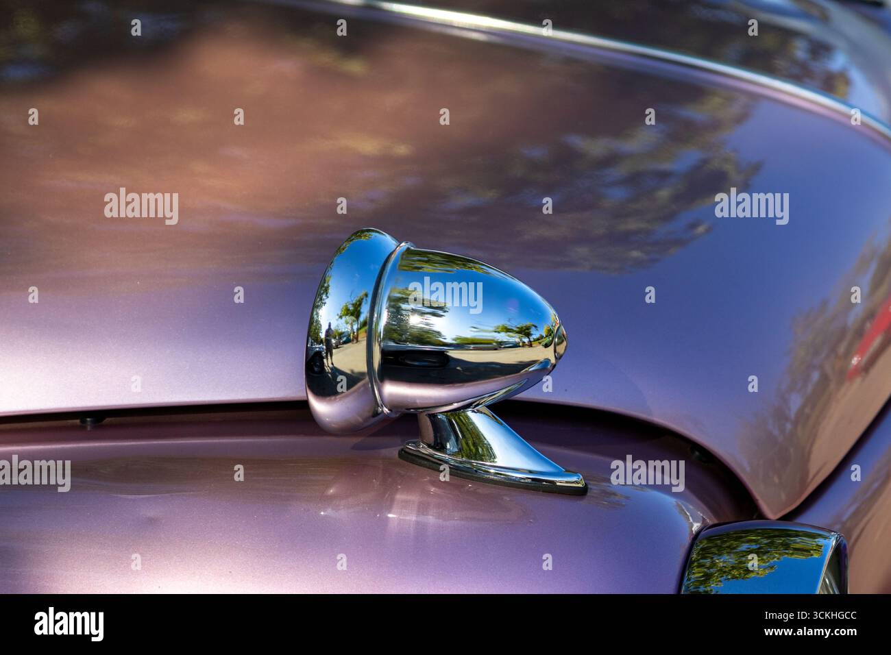 Polished chrome wing mirror reflecting trees and street on a classic car, showcasing vintage automotive design Stock Photo