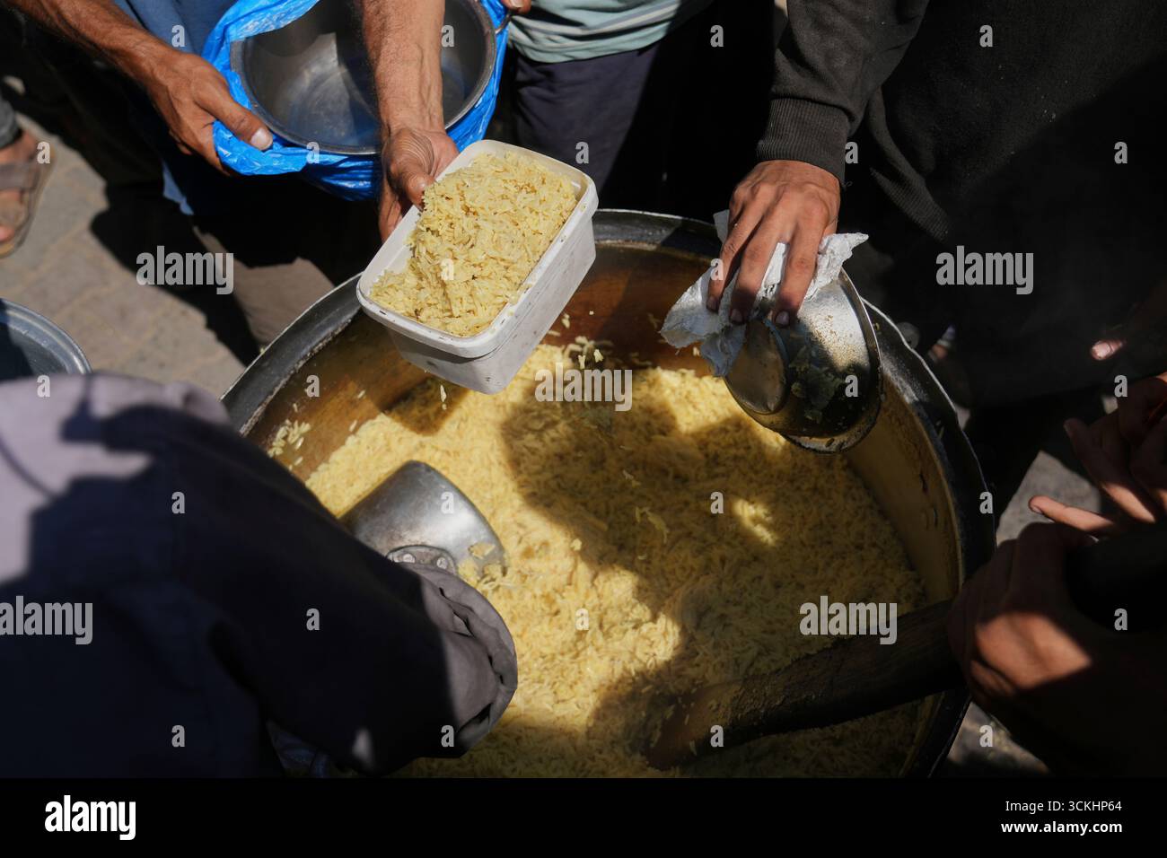 Palestinians receive donated food at a community kitchen in Deir al ...