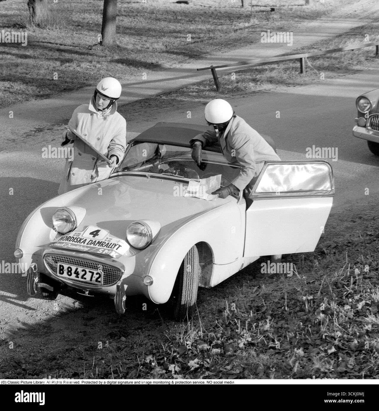 Austin-Healey Sprite MK1 Frogeye: Icon of 1960s Rally Spirit. In this vibrant 1960 image from the Nordic Women's Rally, two female participants stand beside their Austin-Healey Sprite MK1 'Frogeye,' a compact British sports car celebrated for its cheeky, frog-like headlights and revolutionary monocoque body design. Launched in 1958 by Donald Healey Motor Company under BMC, the Sprite offered affordable fun with a 948cc A-series engine delivering 43 hp, rear-wheel drive, and a lightweight 1,500 lbs frame—ideal for spirited driving and motorsport. Its significance lies in democratizing sports ca Stock Photo