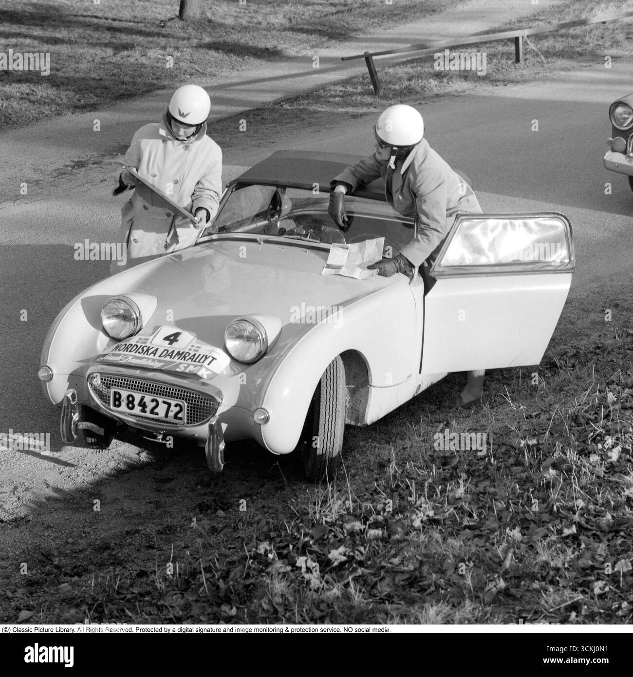 Austin-Healey Sprite MK1 Frogeye: Icon of 1960s Rally Spirit. In this vibrant 1960 image from the Nordic Women's Rally, two female participants stand beside their Austin-Healey Sprite MK1 'Frogeye,' a compact British sports car celebrated for its cheeky, frog-like headlights and revolutionary monocoque body design. Launched in 1958 by Donald Healey Motor Company under BMC, the Sprite offered affordable fun with a 948cc A-series engine delivering 43 hp, rear-wheel drive, and a lightweight 1,500 lbs frame—ideal for spirited driving and motorsport. Its significance lies in democratizing sports ca Stock Photo