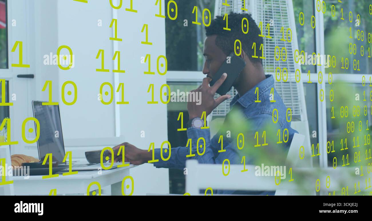 Man typing on laptop and talking on smartphone on terrace, with floating binary code Stock Photo