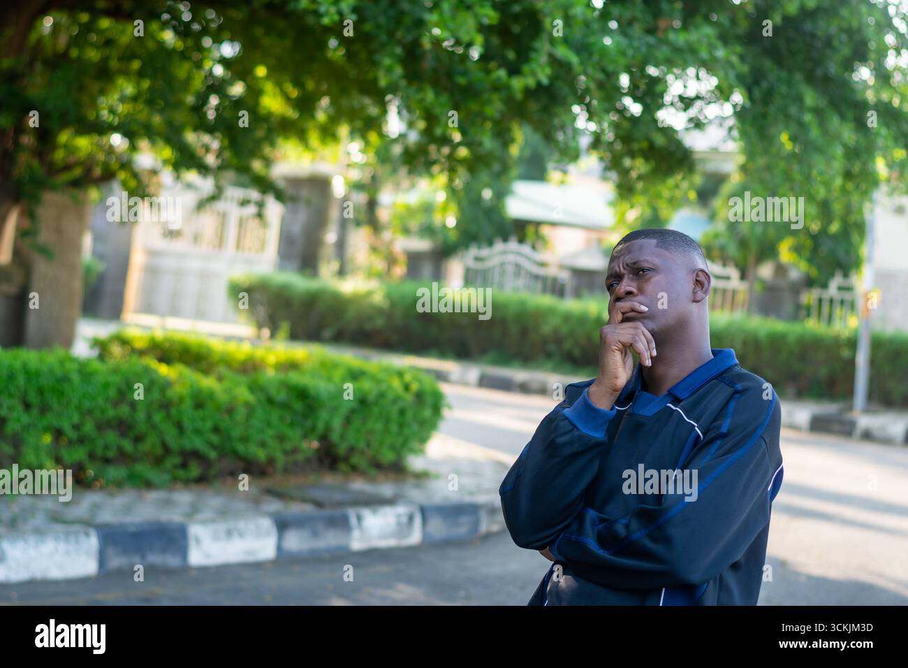 Young African man touching his jaw thinking with a confused and worried expression, isolated on white background. Concept of stress, problem solving, Stock Photo