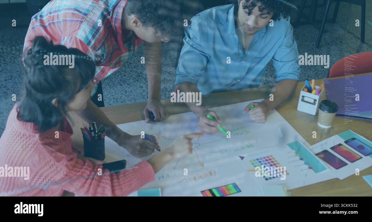 Collaborating professionals pointing, marking, leaning over office table, with mockups, markers Stock Photo