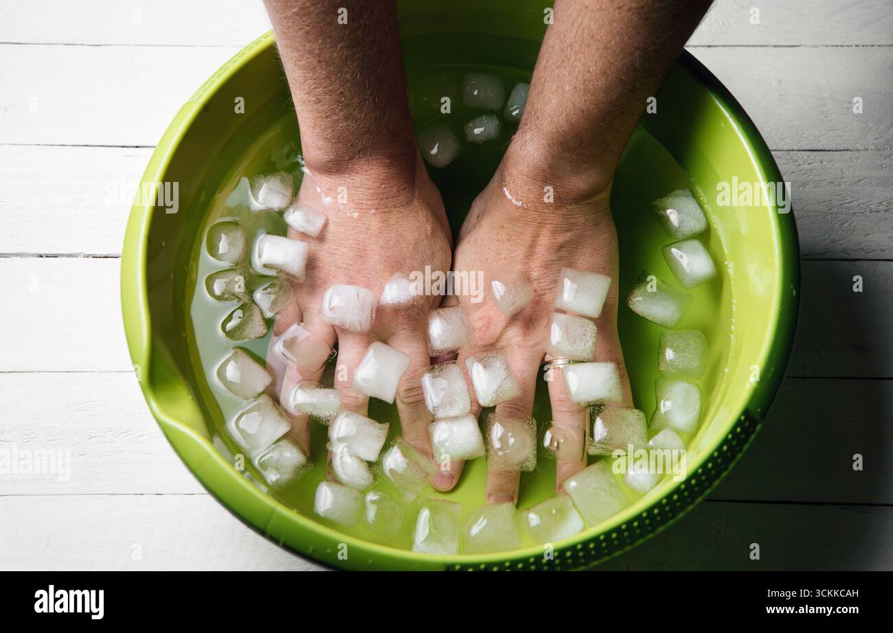 Man holding hands inside ice water bowl with ice cubes. Brief cold ...