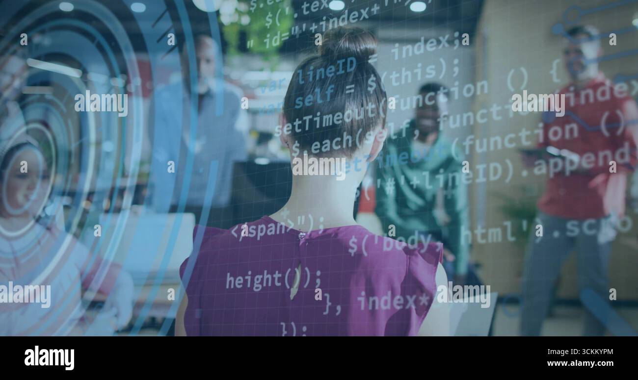 Demonstrating developer in pink blouse typing code with observers in office, with laptop and HUD Stock Photo