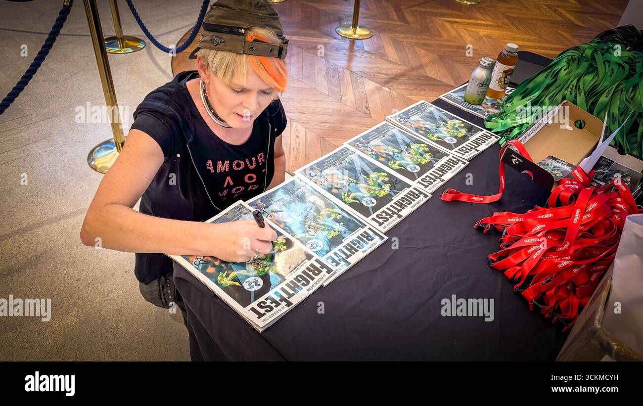 Julie Edwards, the frightfest “house” photographer signing programmes that feature her work. The signed programmes are prizes for attendees. - Smartphone Captured Stock Image