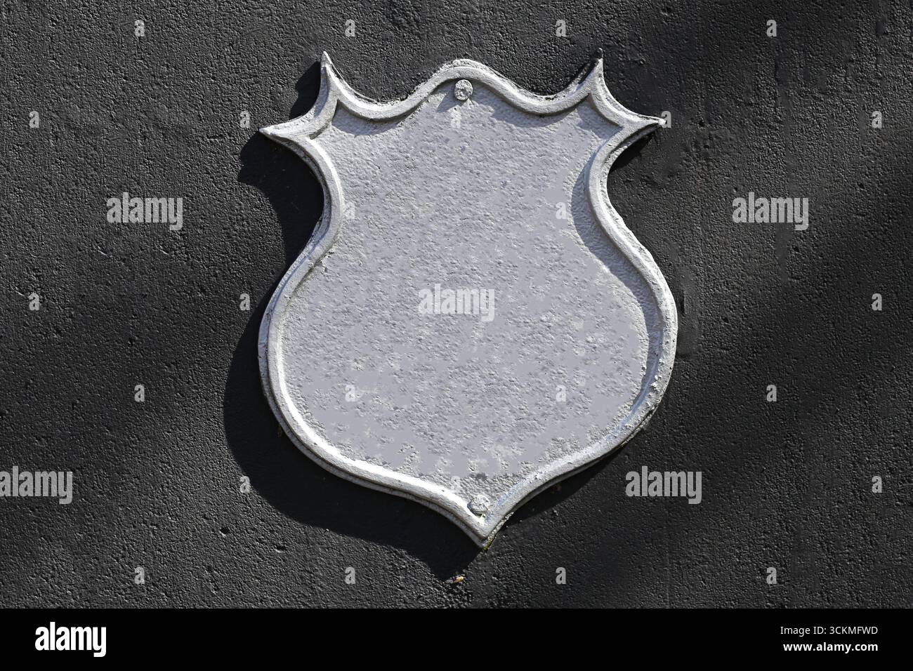 Metal shield sign on black wall. Blank empty emblem plaque with silver surface. Decorative iron shape for design or symbol. Rustic industrial backgrou Stock Photo