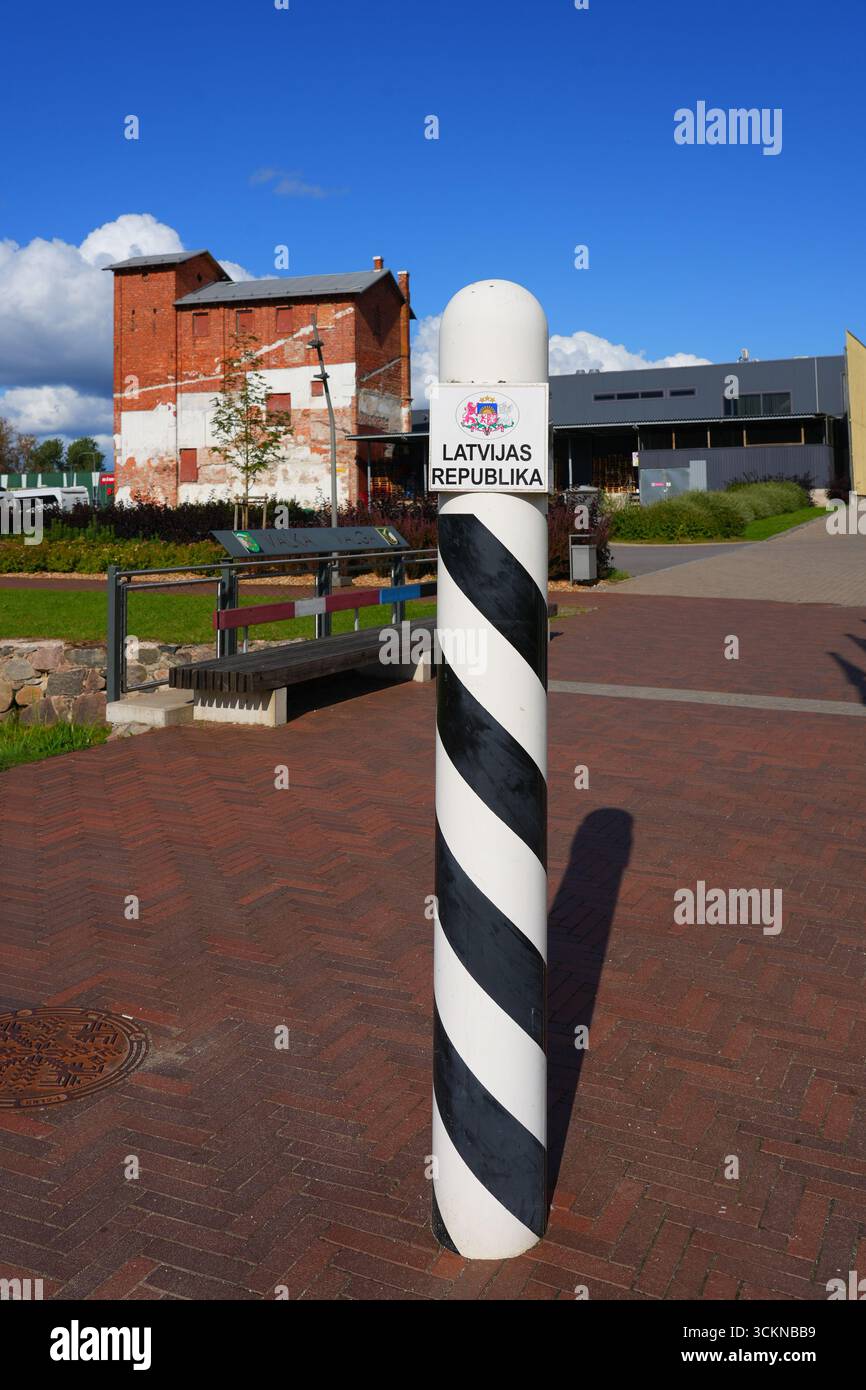 White border post with black stripes and the national emblem of Latvia marked "Latvijas Republika" at the open Valka–Valga border between Latvia and E Stock Photo