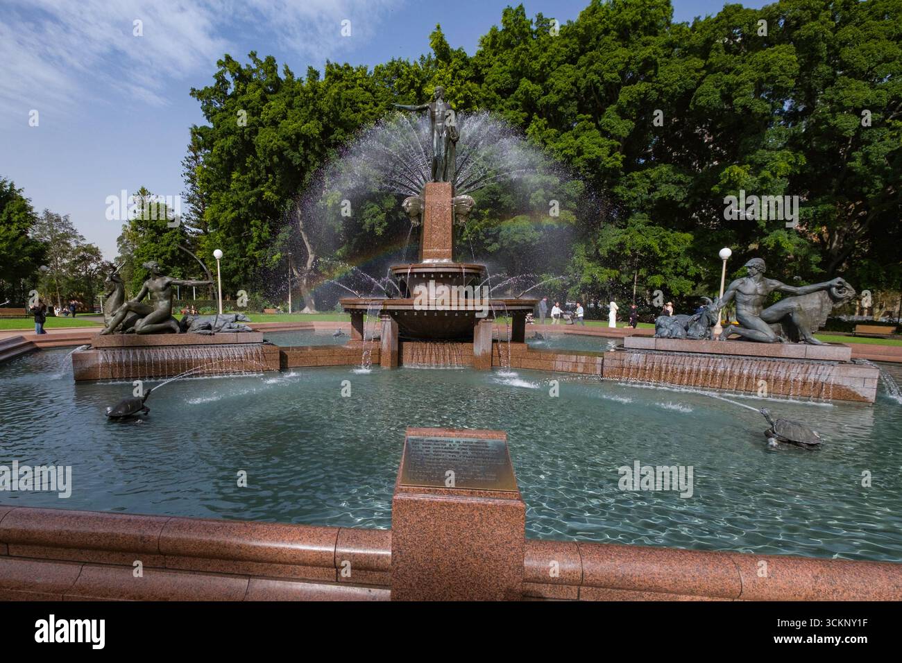 Archibald Memorial Fountain surrounded by intricate sculptures, located in a serene urban park lush with greenery under a clear blue sky, Sydney Stock Photo