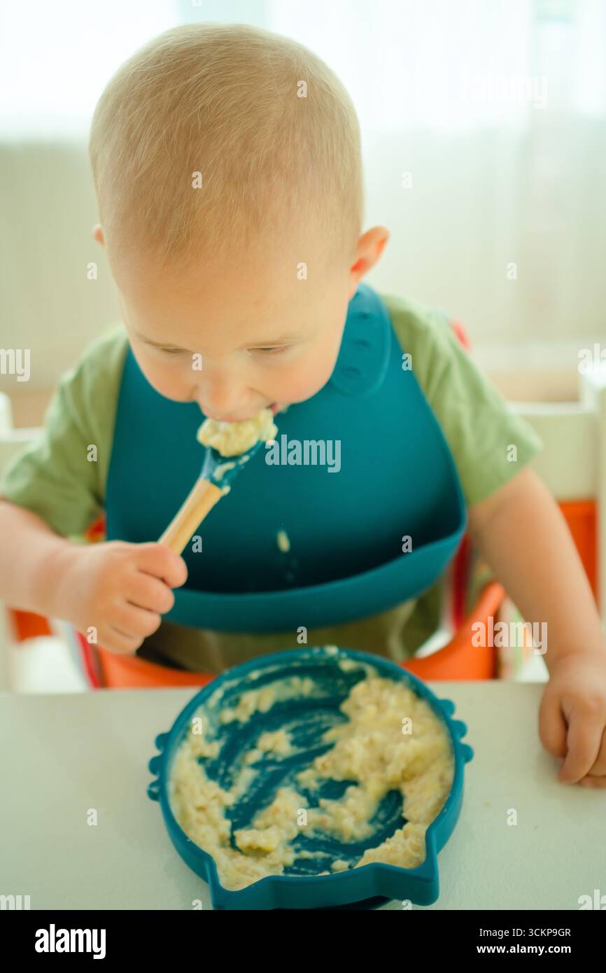 Bird's eye view of toddler eating nutritious porridge independently, capturing important weaning milestone and feeding development from above. Stock Photo