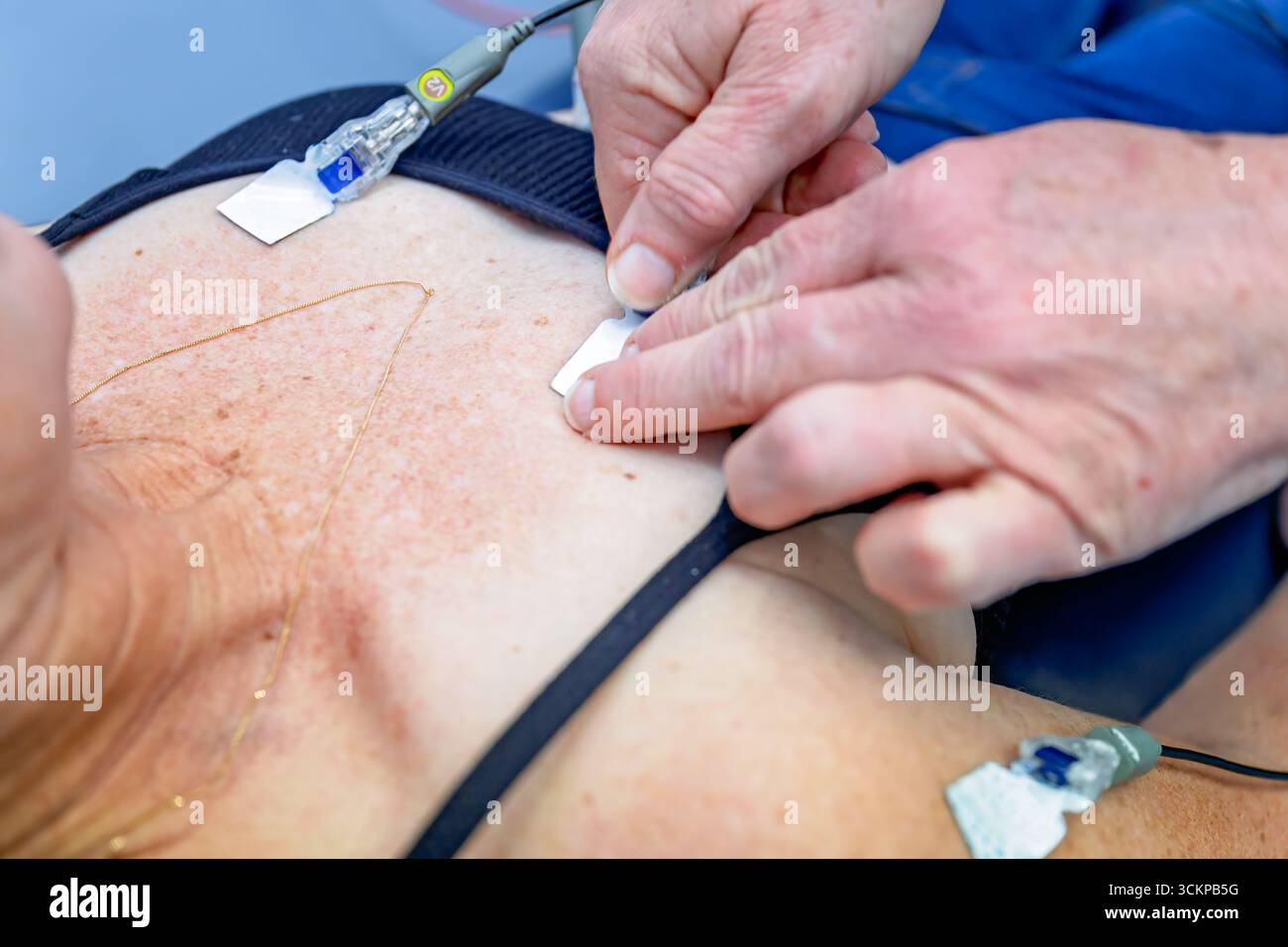 nurse applying ECG leads to female patient, australia GP general practice, medical healthcare clinic Stock Photo