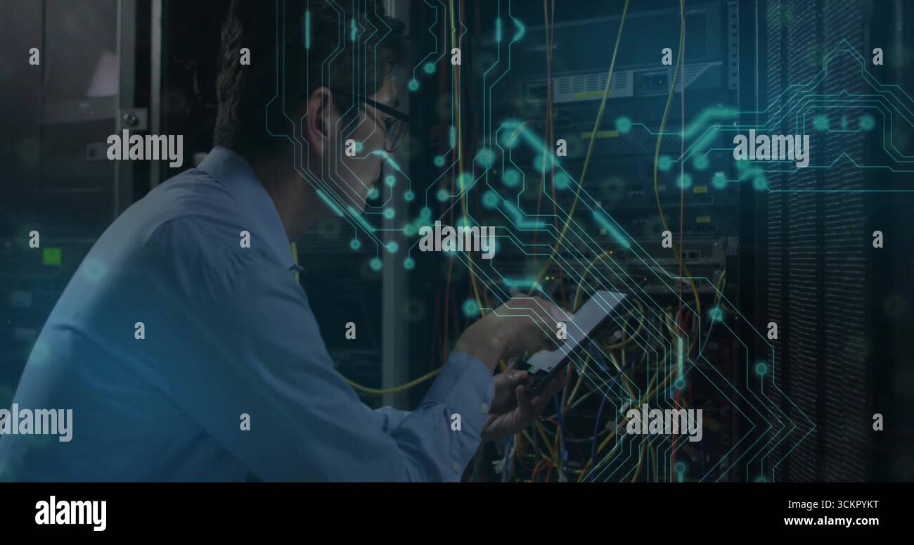 Crouching network engineer wearing tie configuring servers with cables ...