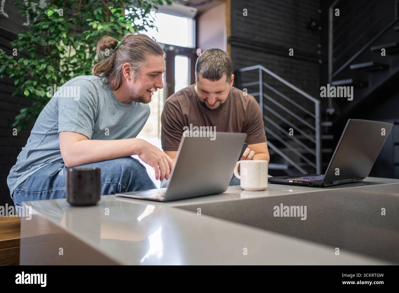Two laughing It Software engineers working on project and programming in coffee shop. Successful start up project concept. Stock Photo