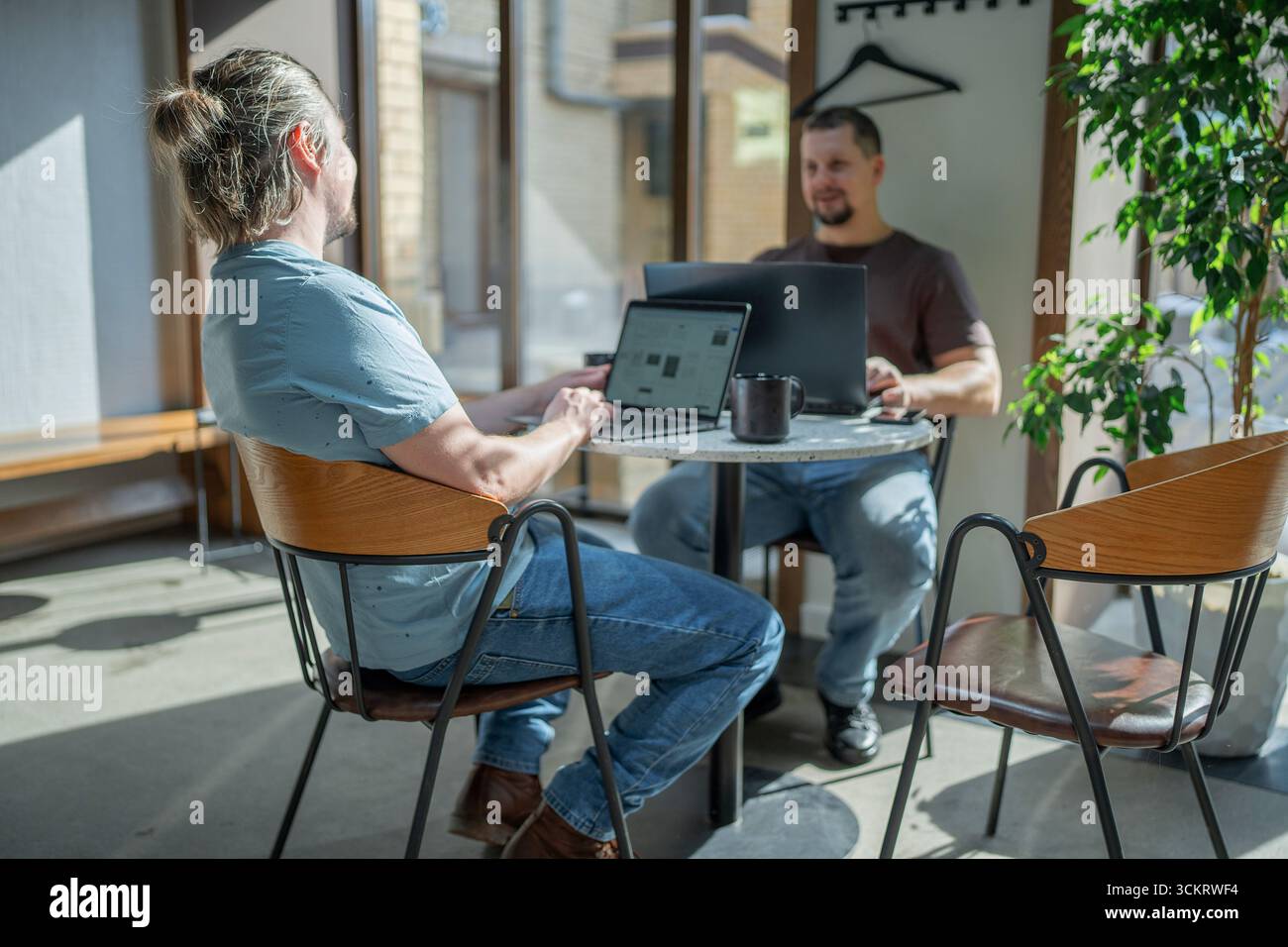 Two laughing It Software engineers working on project and programming in coffee shop. Successful start up project concept. Stock Photo