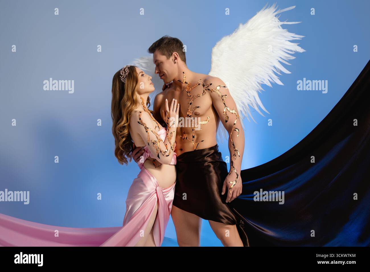 Couple in dramatic costumes pose together against a blue background Stock Photo