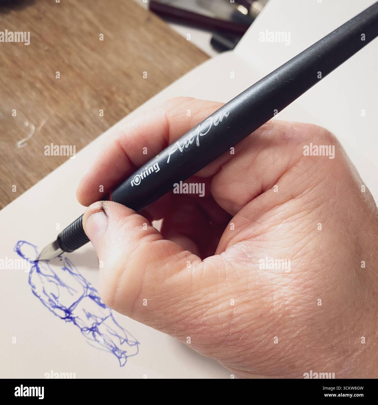 An artists hand, drawing with an ink fountain art pen - Smartphone Captured Stock Image