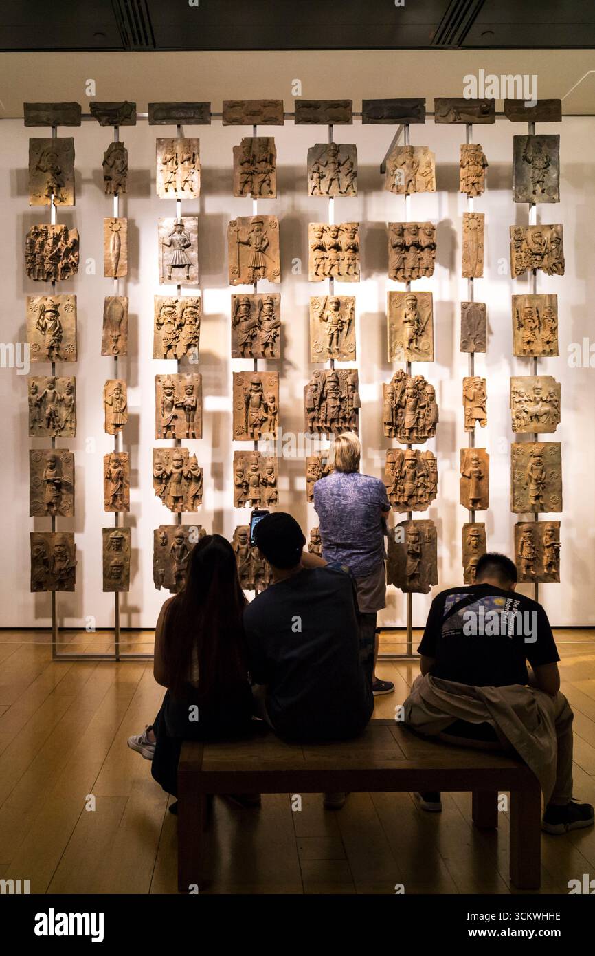 People looking at a display of C16th cast brass plaques from Benin, Nigeria.  On display at the British Museum. Stock Photo