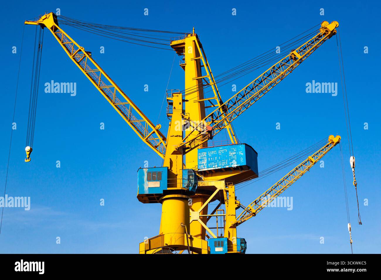 Yellow harbor cranes against the blue sky. Stock Photo