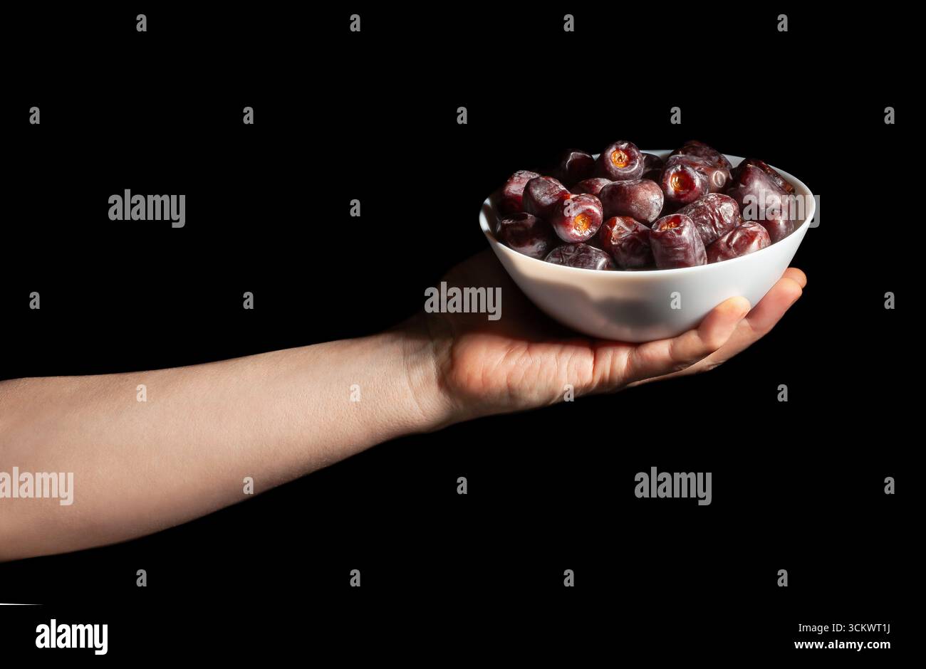 dates fruit in hand on black background Stock Photo