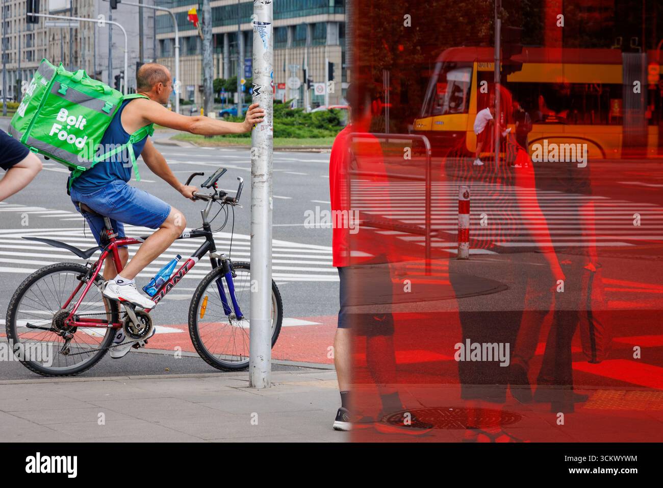 Warsaw, Poland - August 3, 2025: A male courier on a bicycle with a Bolt Food backpack in Warsaw Stock Photo