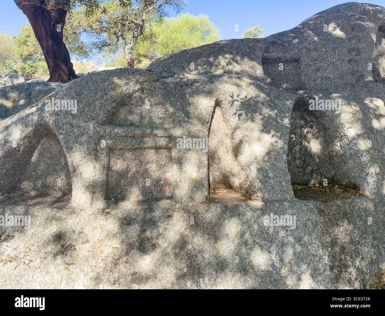 Ancient rock-cut altar with multiple niches under oak trees in Sardinia ...