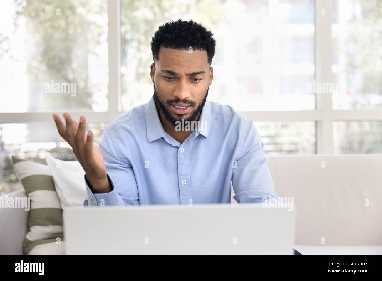 Busy young man working remotely talking by videocall using notebook Stock Photo