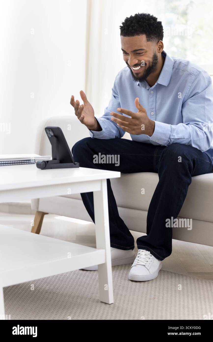 Smiling young guy speak by videocall using phone on holder Stock Photo