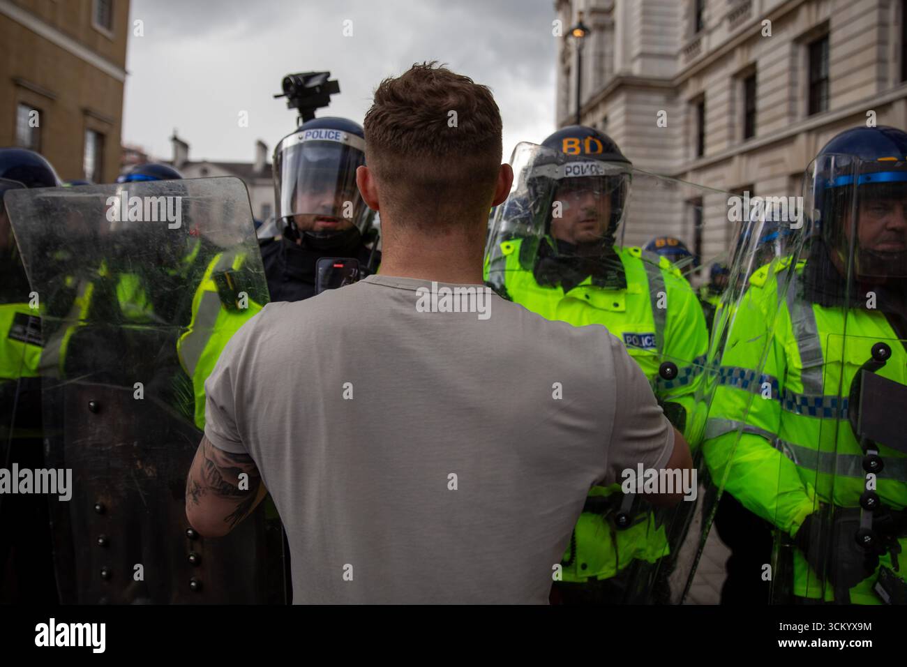 A protestor stands in-front of Metropolitan Police riot officers. The ...