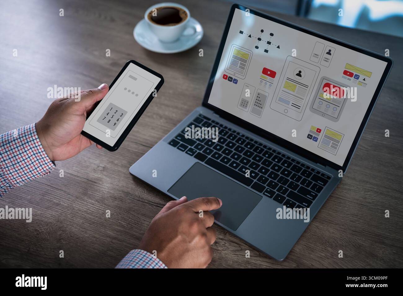 Mobile app interface concept with designer using smartphone and laptop, showing wireframe and UI UX layout on screen, symbolizing application developm Stock Photo