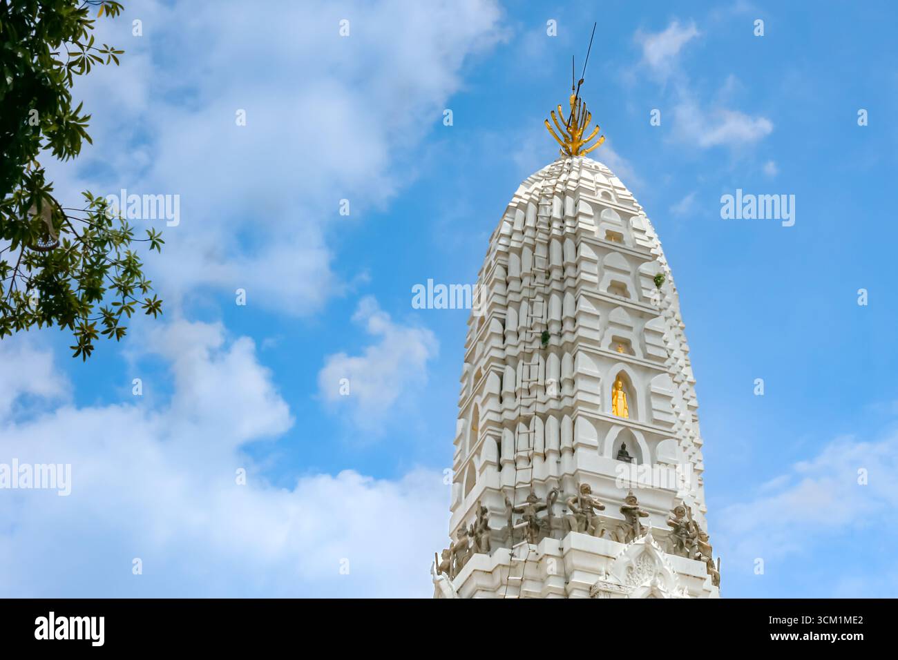 Wat Rakhang Kositaram in Bangkok, Thailand. White stupa with golden Buddha statues under bright blue sky, symbol of Thai temple heritage and culture. Stock Photo