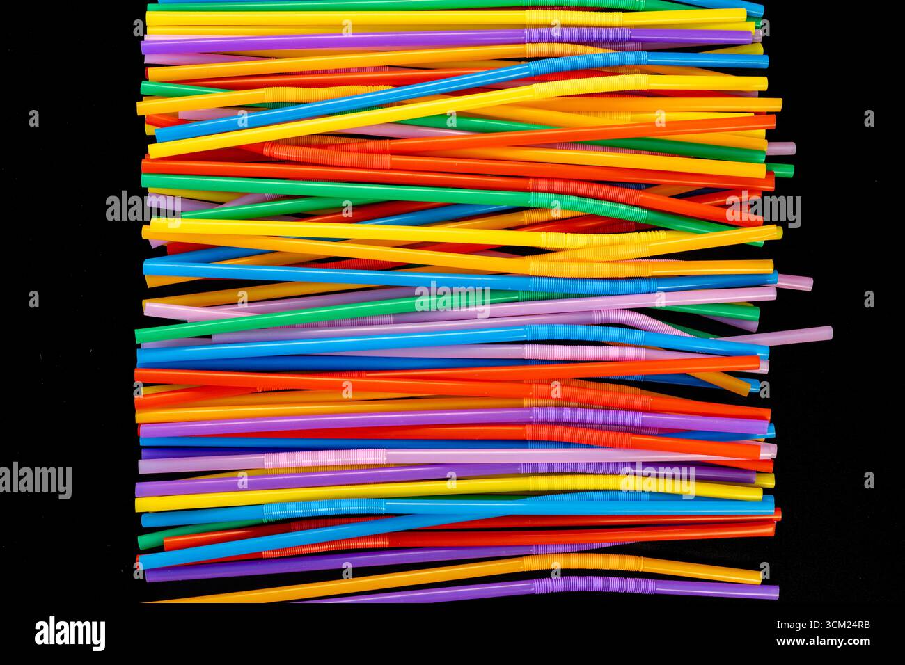 Horizontal Stack of Colorful Bendable Drinking Straws on Black Background Stock Photo